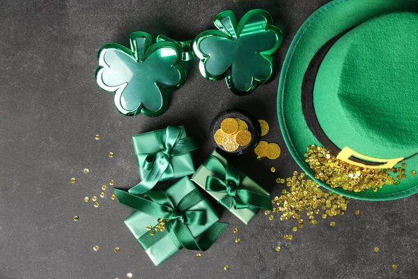 Plastik gözlüklü cüce şapka, hediye kutuları ve siyah grunge arka planda pullar. Aziz Patrick Günü