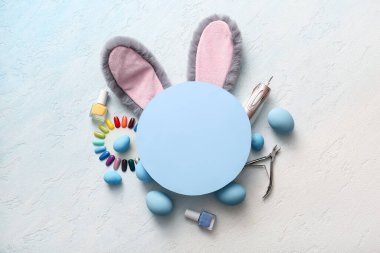 Paskalya yumurtalı tavşan kulakları, manikür aletleri ve açık mavi grunge arka planda boş tebrik kartı.