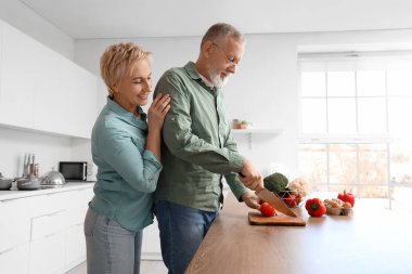 Mutfakta domates kesen olgun bir çift.