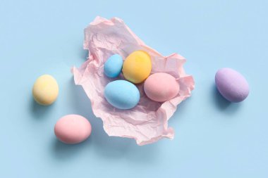 Mavi arka planda boyalı Paskalya yumurtaları olan buruşuk kağıt.