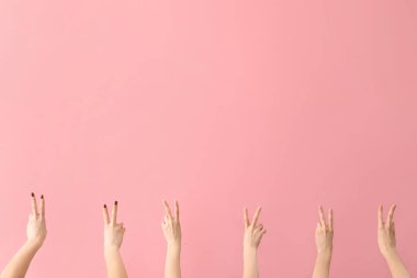 Pembe arka planda barış jestleri gösteren kadın elleri