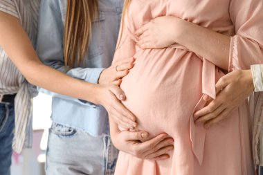 Bebek partisinde genç hamile bir kadının karnına dokunan kız arkadaşlar, yakın plan.