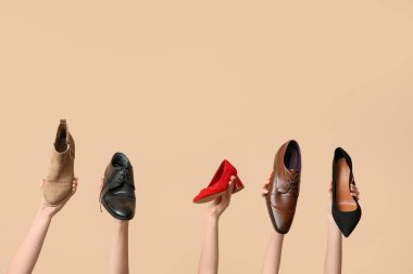 Bej arka planda farklı şık ayakkabıları olan kadın elleri. Ayakkabı tamiri kavramı