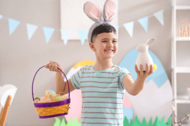 Paskalya sepetiyle tavşan kulağı takan şirin bir çocuk.