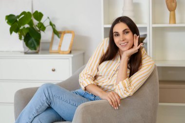 Evdeki koltukta oturan güzel kadın.