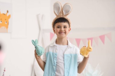 Evde paskalya tavşanlarıyla tavşan kulağı takan şirin bir çocuk.