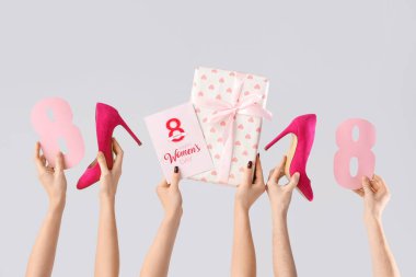 Hediye kutusu olan kadın elleri, şenlikli kartpostal ve beyaz arka planda yüksek topuklu ayakkabılar. Uluslararası Kadınlar Günü için Alışveriş