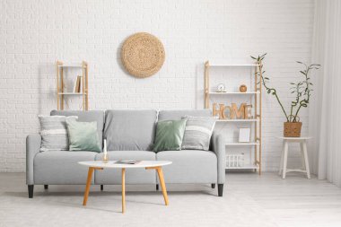 Gri kanepe, masa ve raf üniteleriyle modern oturma odasının içinde.