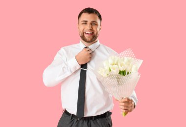 Pembe arka planda çiçekli yakışıklı bir adam.