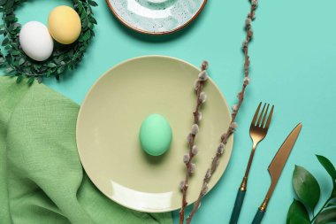 Paskalya için turkuaz arka planda yumurta, çelenk ve söğüt dallarıyla güzel bir masa.