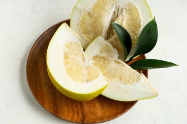 Tahta tabakta taze meyve dilimleri ve beyaz arka planda yapraklar.