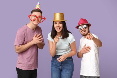 Mor arka plandaki izleyiciye bakan komik kılık değiştirmiş genç arkadaşlar. 1 Nisan kutlamaları