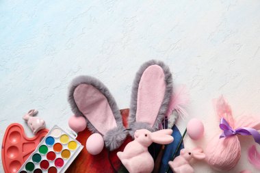 Paskalya yumurtalı tavşan kulakları ve açık mavi arka planda boya malzemeleri.