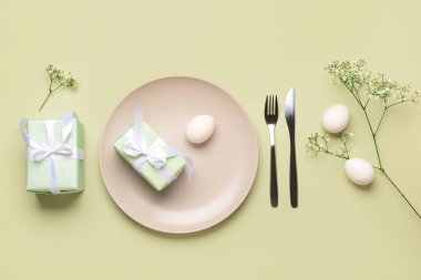 Yeşil arka planda hediyeler, çiçekler ve yumurtalarla güzel bir Paskalya masası.