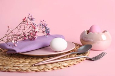 Paskalya için güzel bir masa, pembe arka planda yumurtalar ve çiçekler.