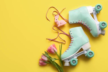 Sarı arka planda güzel laleleri ve oyuncak tavşanları olan klasik patenler. Paskalya kutlaması