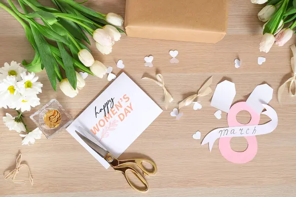 Tebrik kartı, hediye kutusu, çiçekler ve tahta arka planda ambalaj malzemeleri olan kompozisyon. Uluslararası Kadınlar Günü