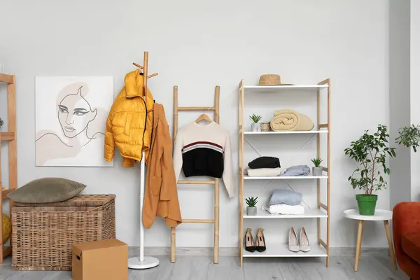 Interior of modern dressing room with clean clothes on shelving unit and rack
