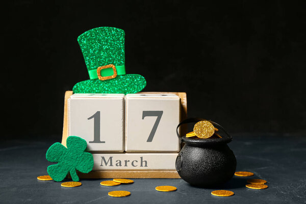 Лепрекон горшок с золотыми монетами и деревянный календарь на столе на темном фоне. Празднование Дня Святого Патрика