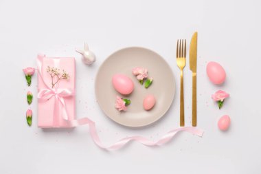 Beyaz arka planda pembe hediyeler, çiçekler ve yumurtalar olan şirin Paskalya sofrası.