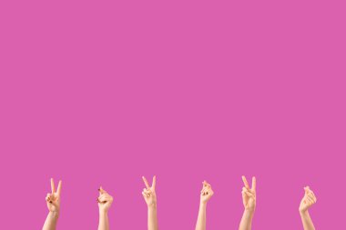 Kadın elleri barış jestleri gösteriyor ve mor arka planda bir şey tutuyor.