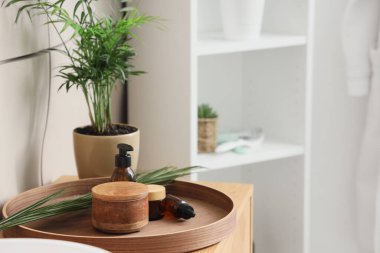 Banyo masasında cilt bakımı ürünleri ve palmiye yaprağı olan tepsi.