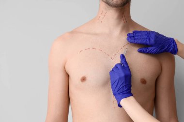 Plastik cerrah, neşter ve adamın göğsünde hafif arka planda izler var. Yakın plan.