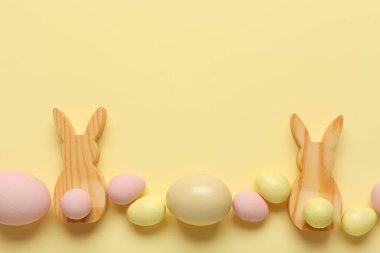 Bej arka planda boyanmış Paskalya yumurtaları ve ahşap tavşanlarla kompozisyon