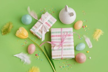 Paskalya hediyeleri, yeşil arka planda boyanmış yumurtalar ve tavşan figürü.