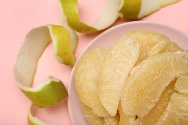 Meyve parçalı bir tabak ve pembe arka planda kabuk.