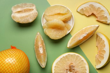 Renkli arka planda dilimleri olan tatlı pomelo.