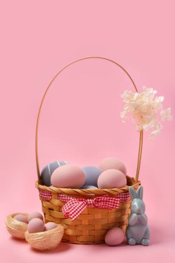 Boyanmış Paskalya yumurtaları, tavşancık ve pembe arka planda çiçekler.