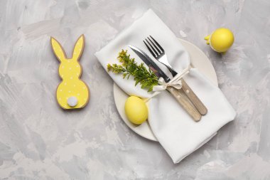Paskalya yumurtaları, peçete ve çatal bıçak seti ve grunge grisi arka planda şık masa dekorları.