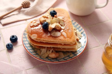 Kalp şeklinde leziz gözlemeler, pembe fayanslı yaban mersini ve fındıklar, yakın plan. Sevgililer Günü kutlaması