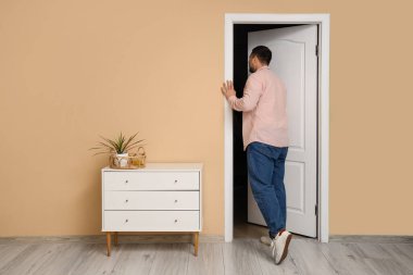 Genç adam odada açık kapıdan giriyor.