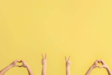 Sarı arka planda barış ve kalp hareketleri gösteren kadın elleri