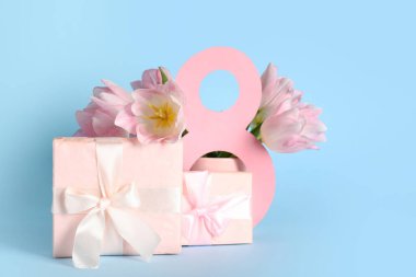 Hediye kutuları ve mavi arka planda güzel pembe laleleri olan kağıttan yapılmış 8 figür. Uluslararası Kadınlar Günü