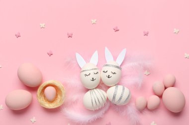 Pembe arka planda yaratıcı Paskalya yumurtaları, yuvaları ve tüyleri olan kompozisyon