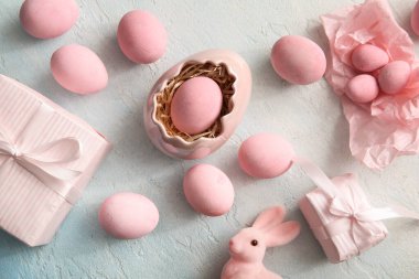 Hediye kutularıyla boyanmış Paskalya yumurtaları ve mavi grunge arka planda bir tavşan.