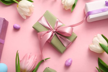 Lale çiçekli Paskalya yumurtaları ve pembe arka planda hediye kutusu.