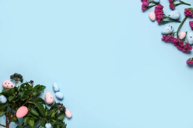 Yeşil dallı Paskalya yumurtaları ve mavi arka planda çiçekler