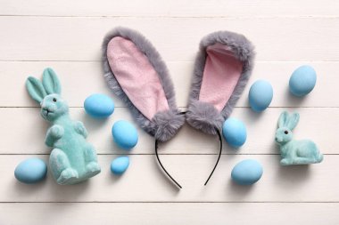 Beyaz ahşap arka planda Paskalya yumurtası olan tavşan kulaklı.