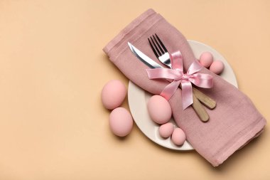 Paskalya yumurtaları, peçete ve bej arka planda çatal bıçak seti ile güzel bir masa.
