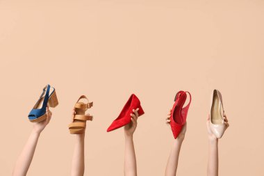Bej arka planda farklı şık ayakkabıları olan kadın elleri. Ayakkabı tamiri kavramı