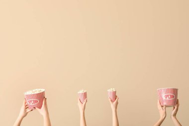 Bej arka planda patlamış mısırlı kovaları tutan eller