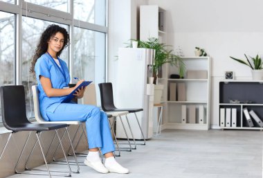 Kadın Afro-Amerikalı stajyer doktor klinikte yazıyor.