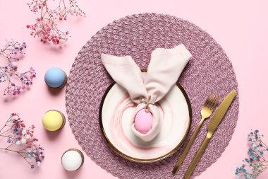 Paskalya için güzel bir masa, pembe arka planda yumurtalar ve çiçekler.