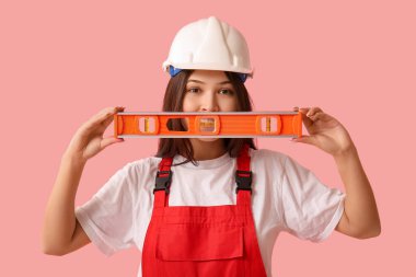 Pembe arka planda ruhsal seviyesi olan genç bir kadın işçi.