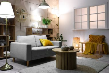 Geceleri altın dekorlu, parlak lambalı ve kanepeli bir oturma odası.