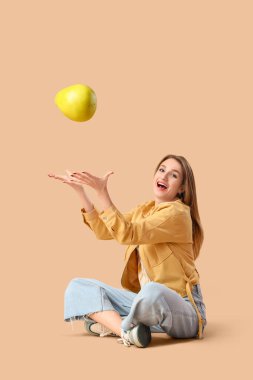 Bej arka planda oturan gülümseyen genç kadın.